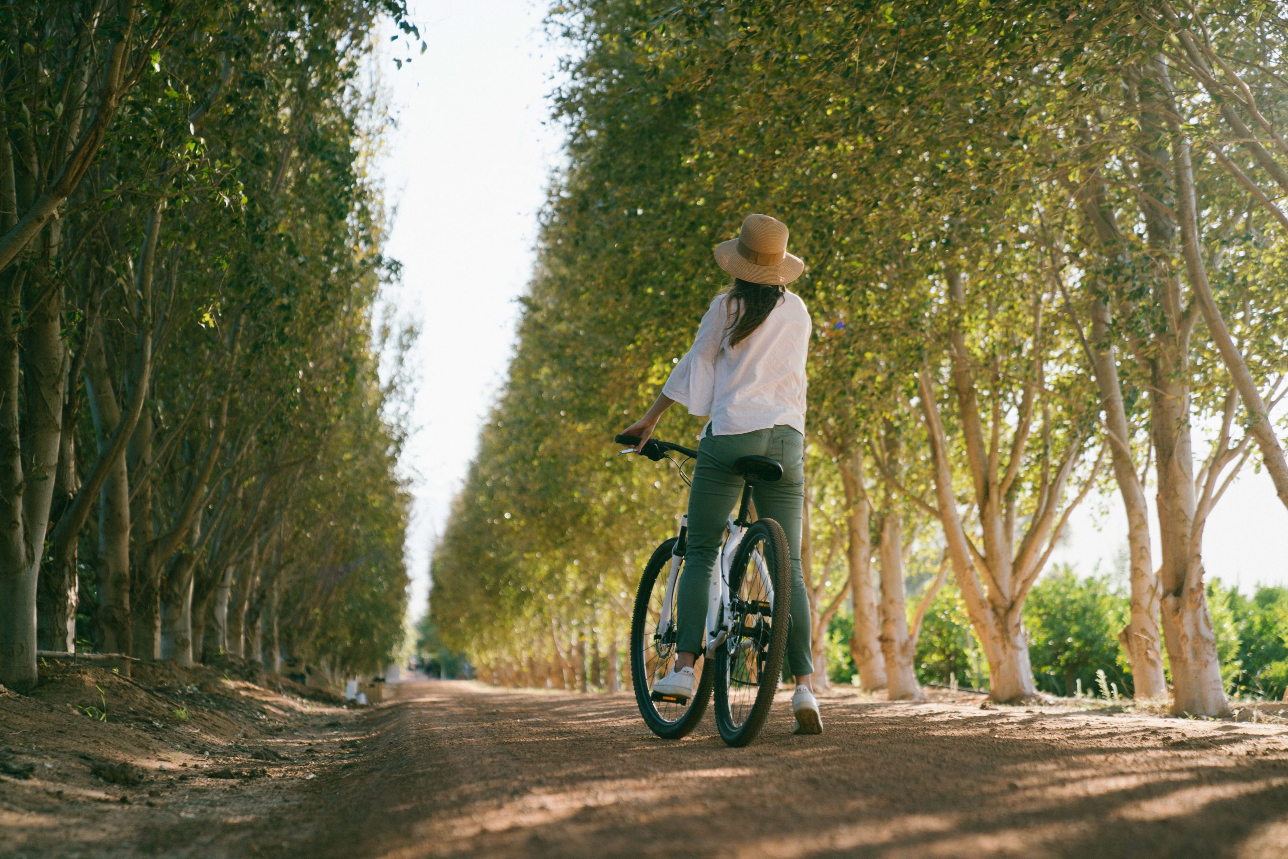 A woman riding a bike down a dirt road.