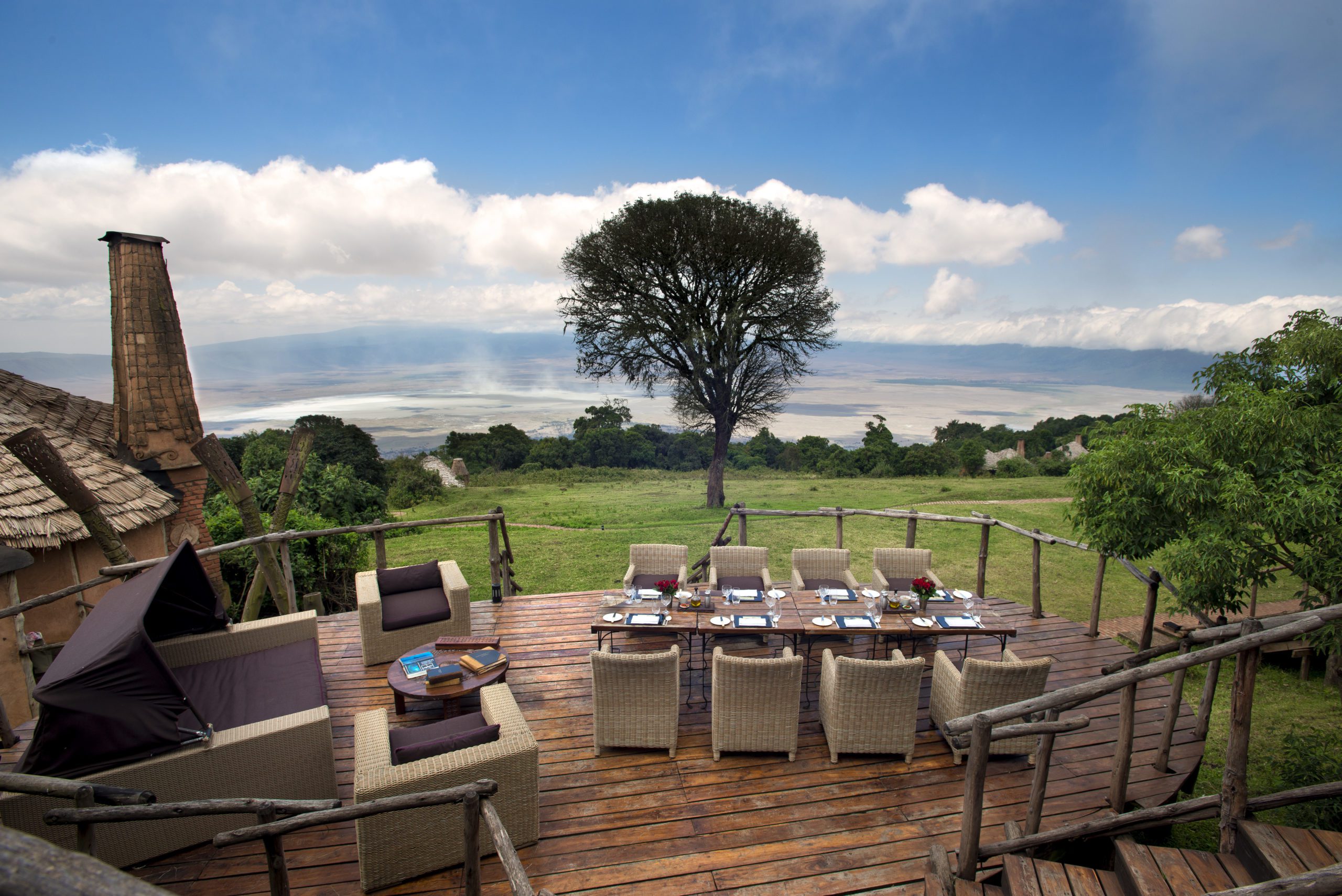 al fresco dinner table on wooden decking overlooking the Ngorongoro Crater with blue skies above