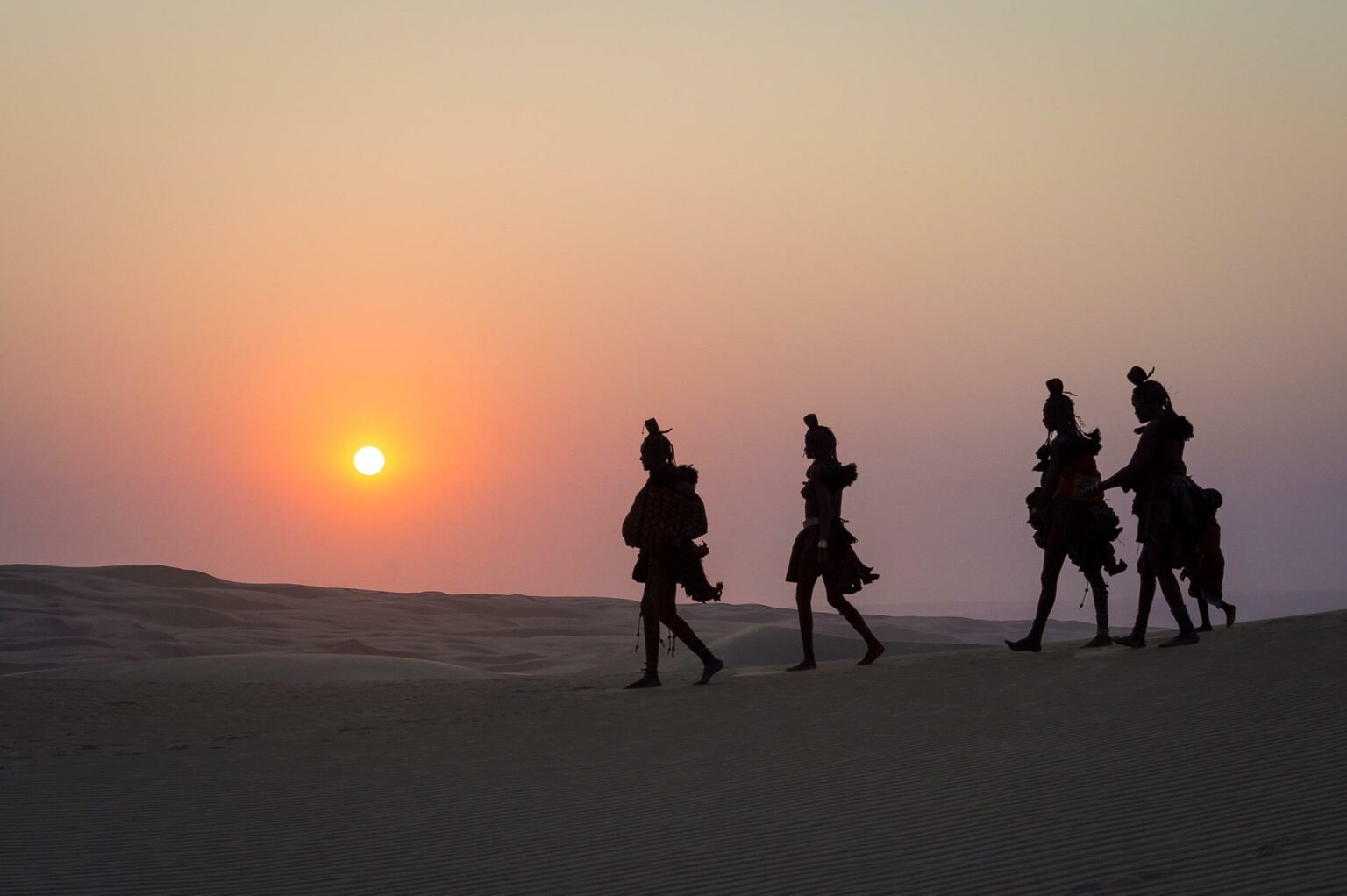 A group of people walking across a desert.