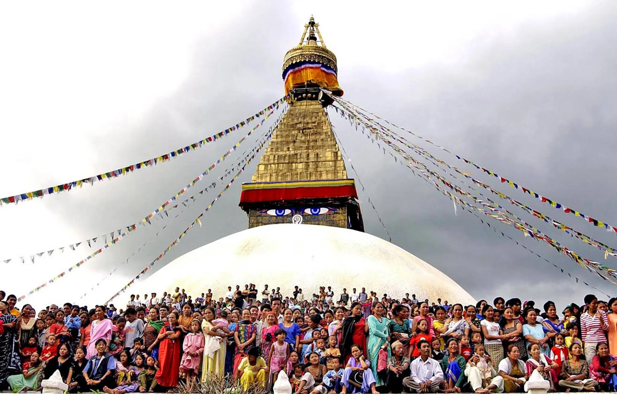 Boudhanath stupa swarmed by worshippers with an ominous sky seen on Nepal holiday