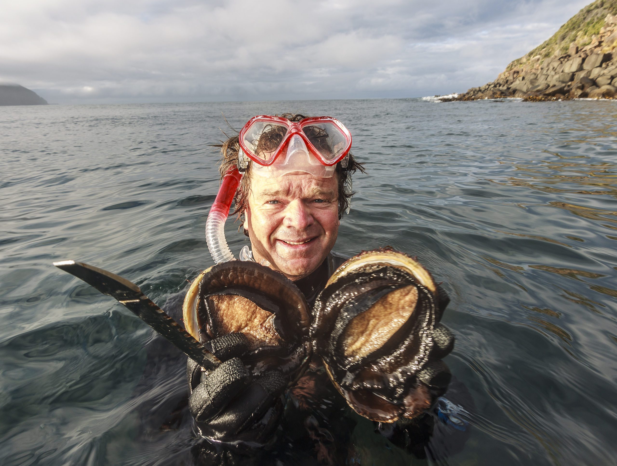 Rob Pennicott holding abalone that he retrieved while snorkeling, intended to be eaten.