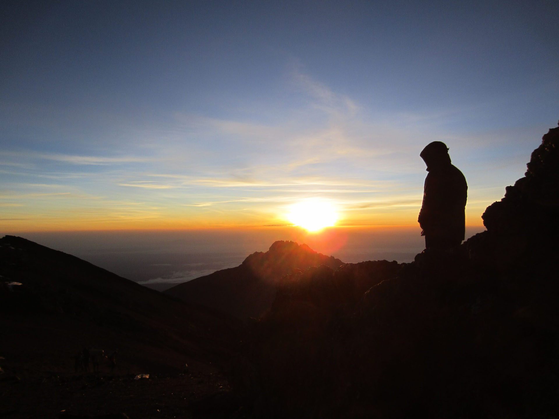 a man standing on top of a mountain at sunset.