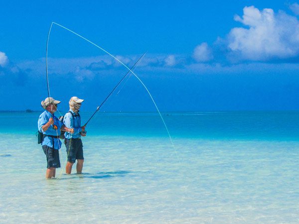 two people fly-fishing at alphonse island in the seychelles in knee-deep water
