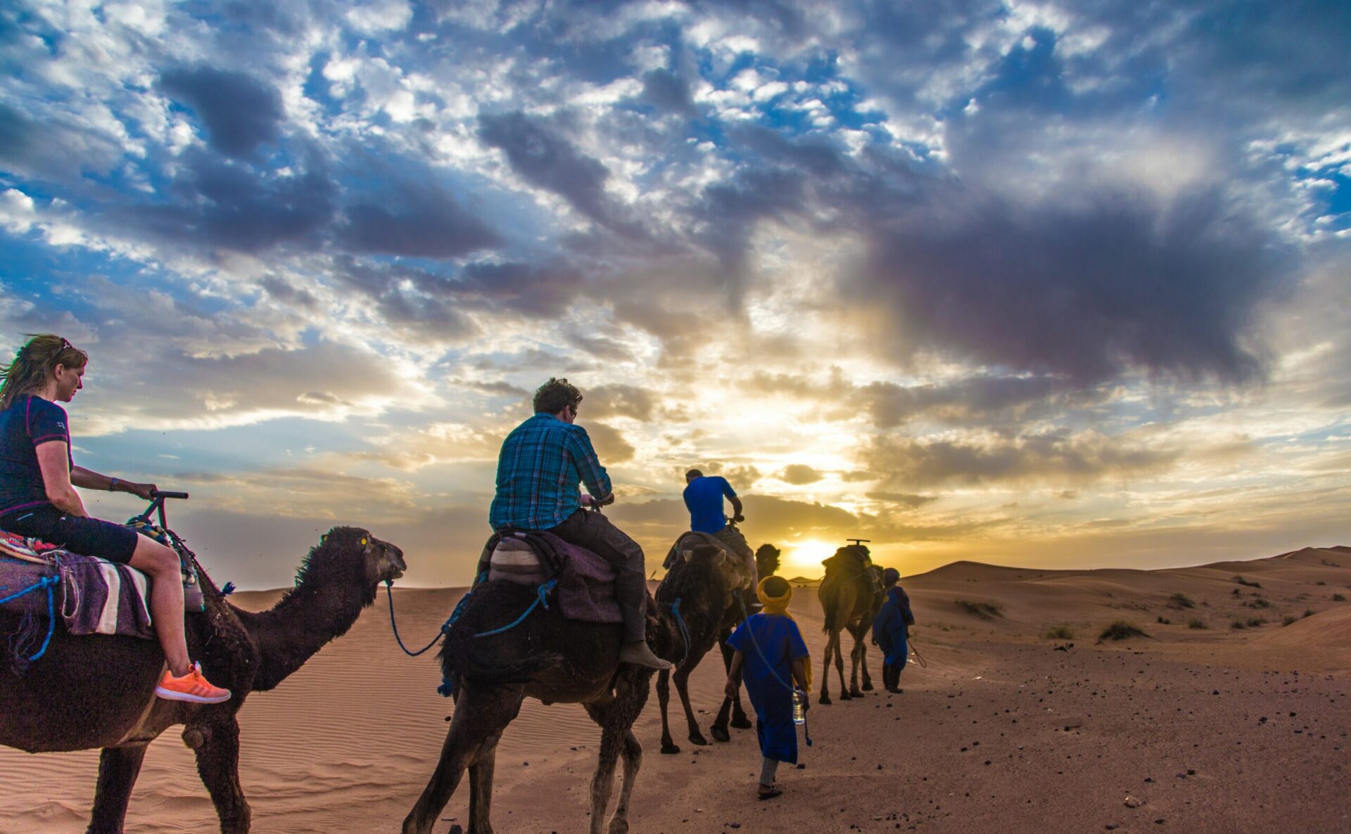 riding camels in the Sahara at Sunset