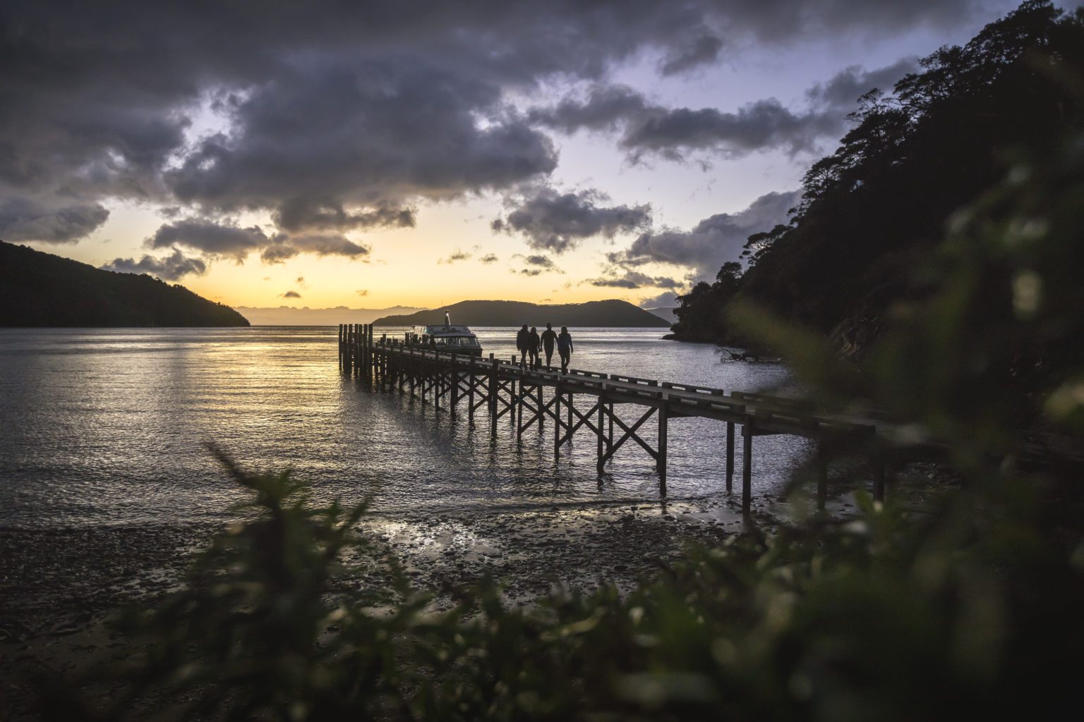 People walking along the jetty in Picton at sunset.