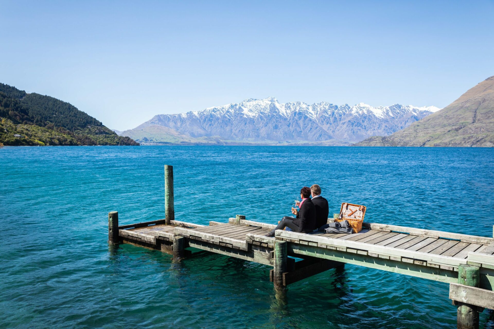 A couple enjoys a private picnic on the jetty at Matakauri Lodge, overlooking Lake Wakatipu and the Remarkables on safari in New Zealand