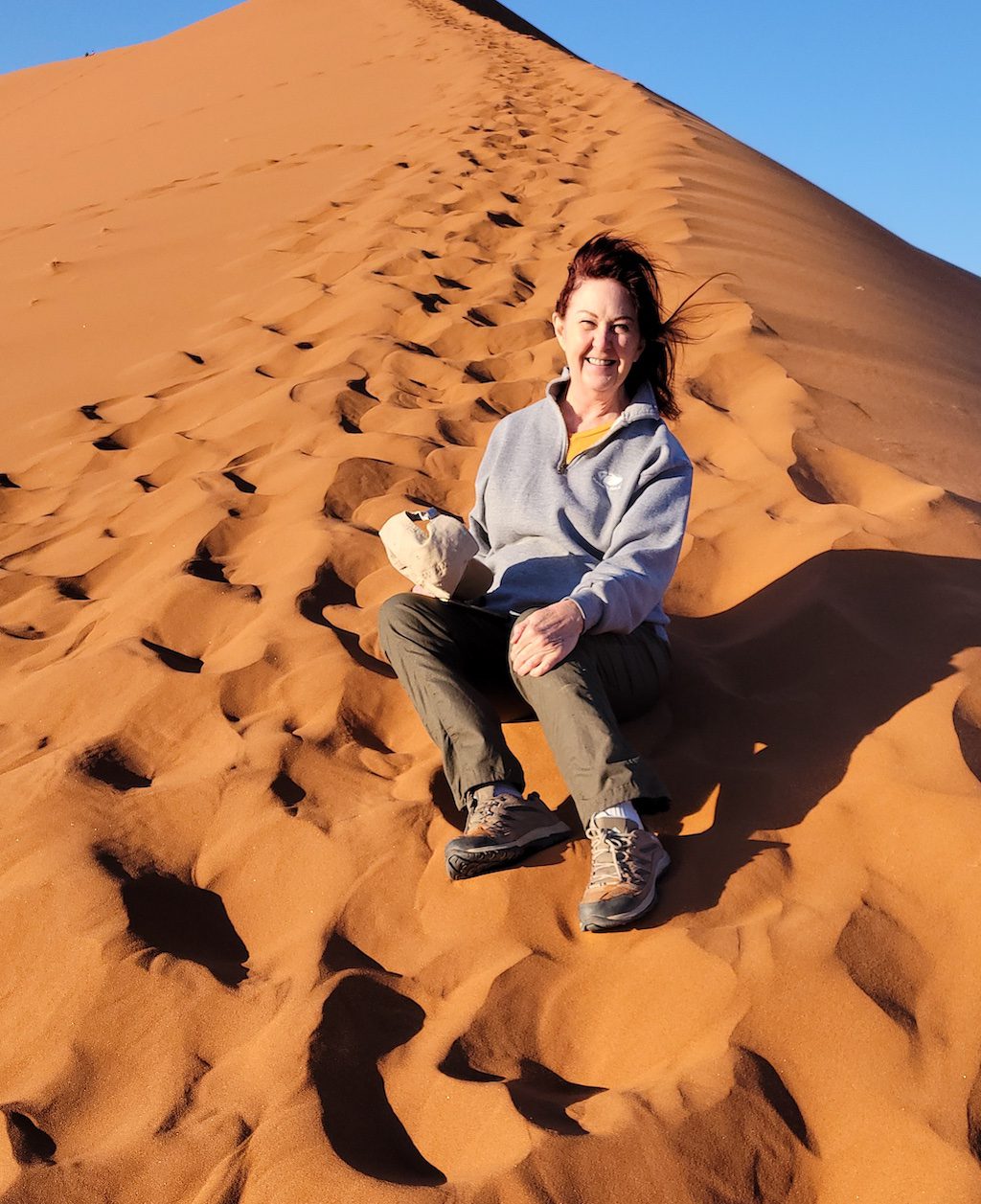 a woman sitting on top of a sand dune.