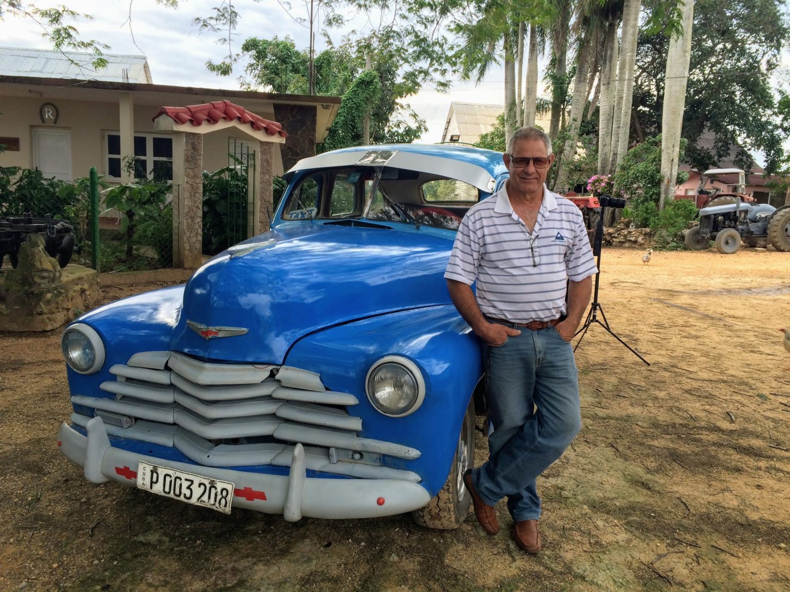 Driver Benino standing beside classic blue car in Vinales