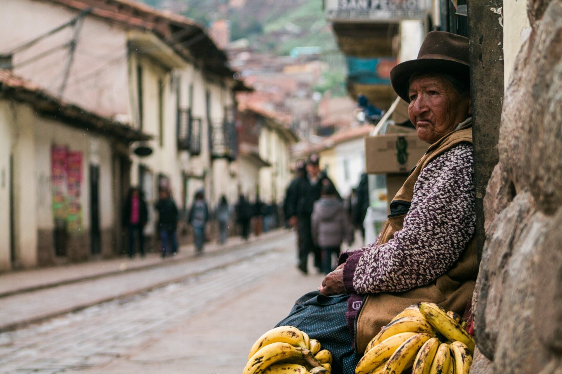 Peruvian woman sitting on side of street in cusco with bananas