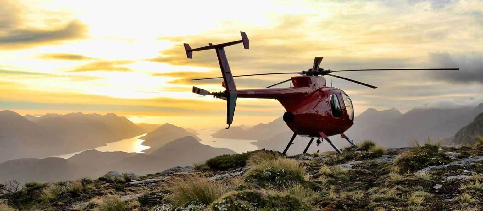 A helicopter lands on a peak in Fiordland overlooking the fiords from Fiordland Lodge.