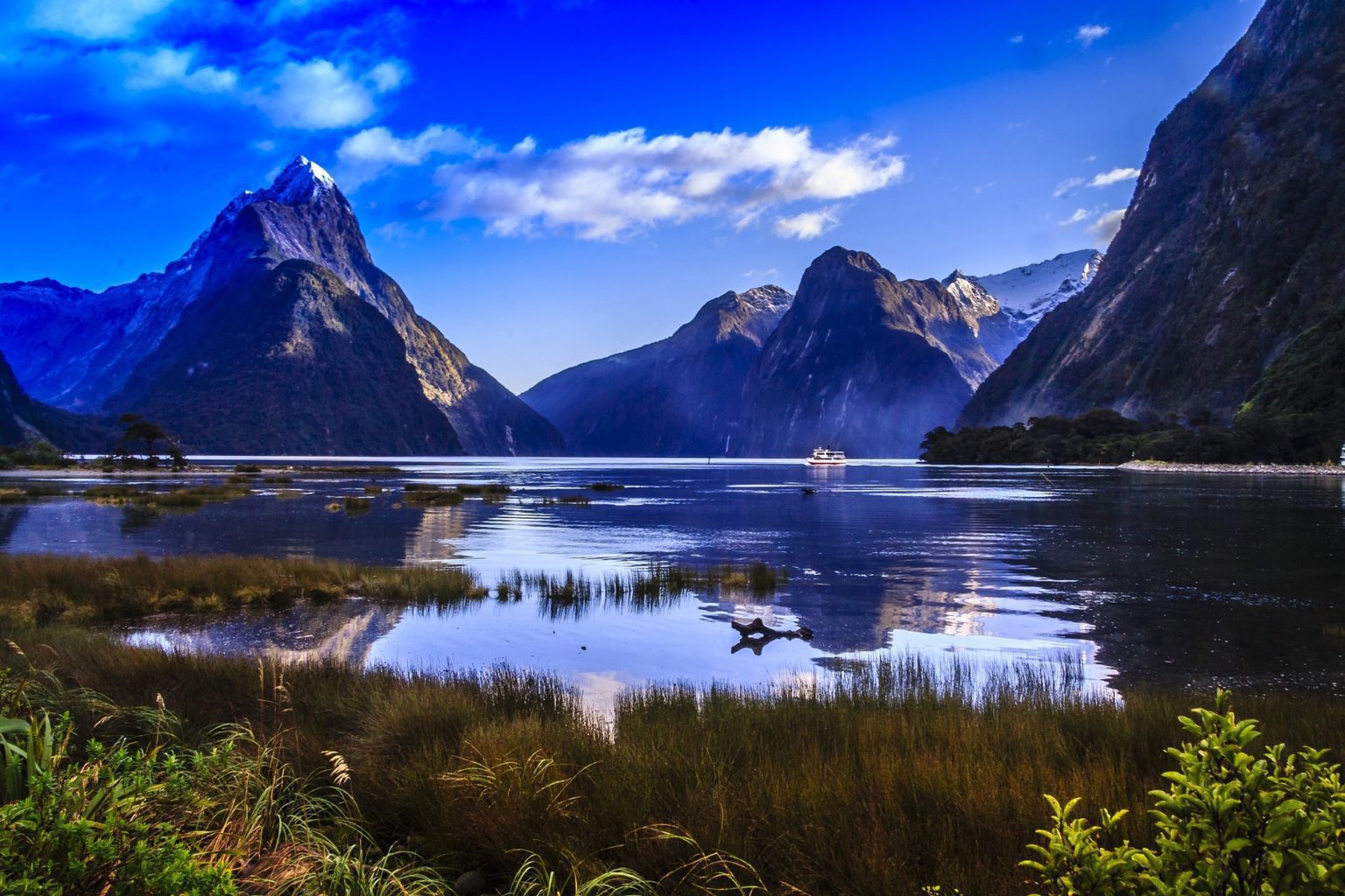dramatic fjord scenery in Fiordland on a clear day with reflecting peaks in the sound on New Zealand tour