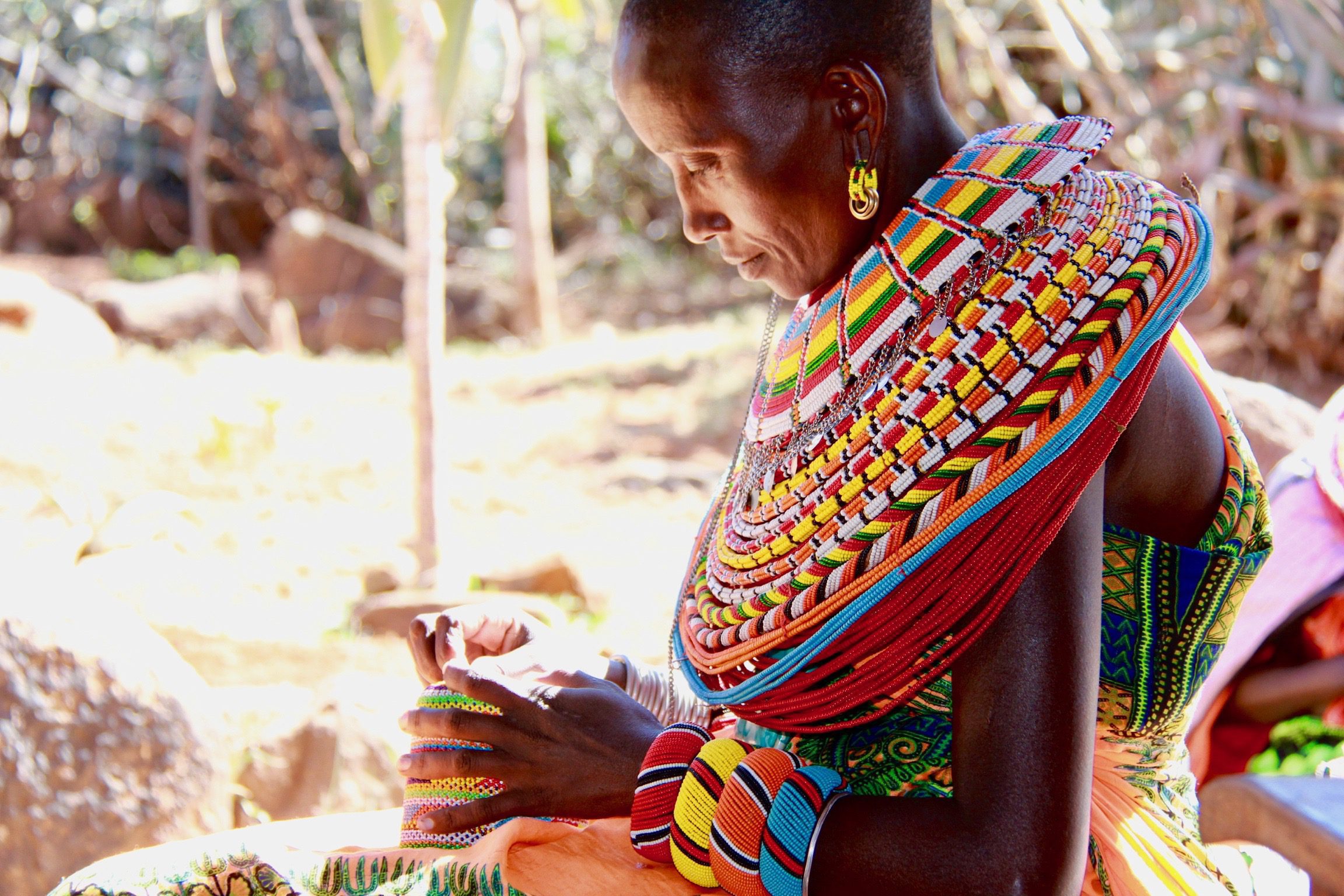 4 favorite activities in Kenya, a samburu woman with an intricately beaded collar focuses on her beading.