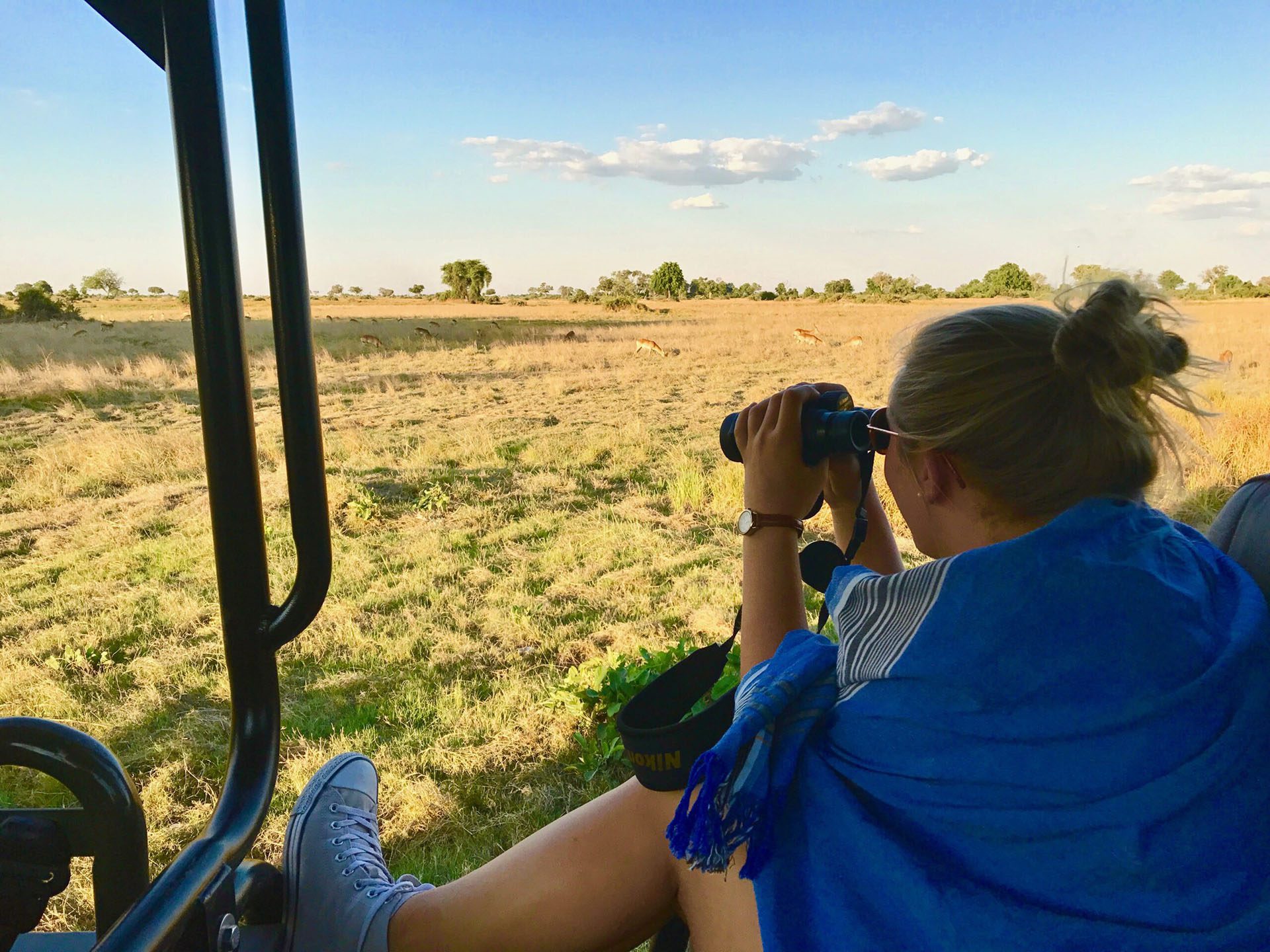 a woman sitting in a vehicle looking through binoculars.
