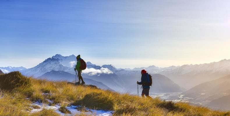 two people hiking up a grassy hill in New Zealand