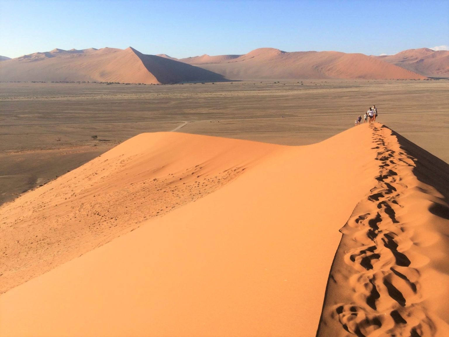 on top of Dune 45 with footprints in the foreground and people walking up in the baackground on our Namibia safari