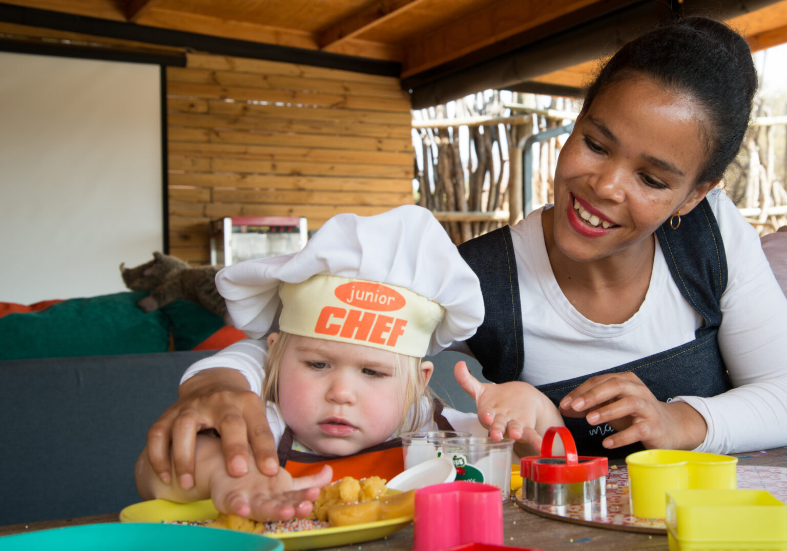 Toddler Chef making cookies with the help of a member of safari camp staff.