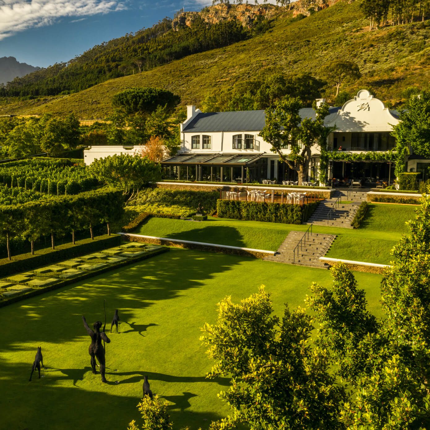 aerial photo over Leeu Estates featuring the white Cape Dutch architecture and lush green hillsides