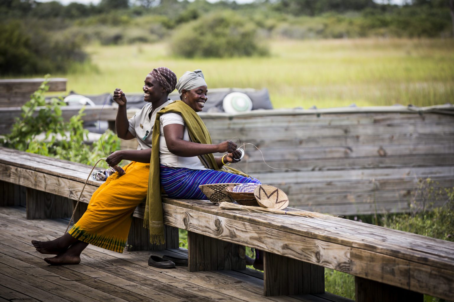 locals laughing and sitting on a bench vumbura plains botswana