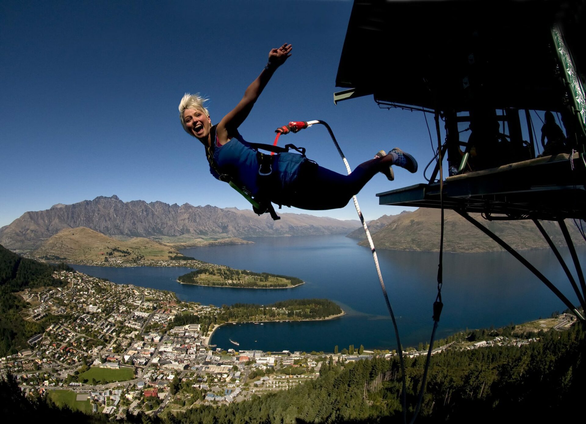 Woman looks at the camera as she bungee jumps off the platform in Queenstown