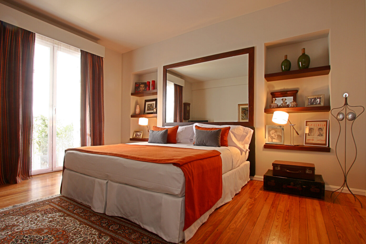 Hotel room with hardwood floors, large bed, and mirror