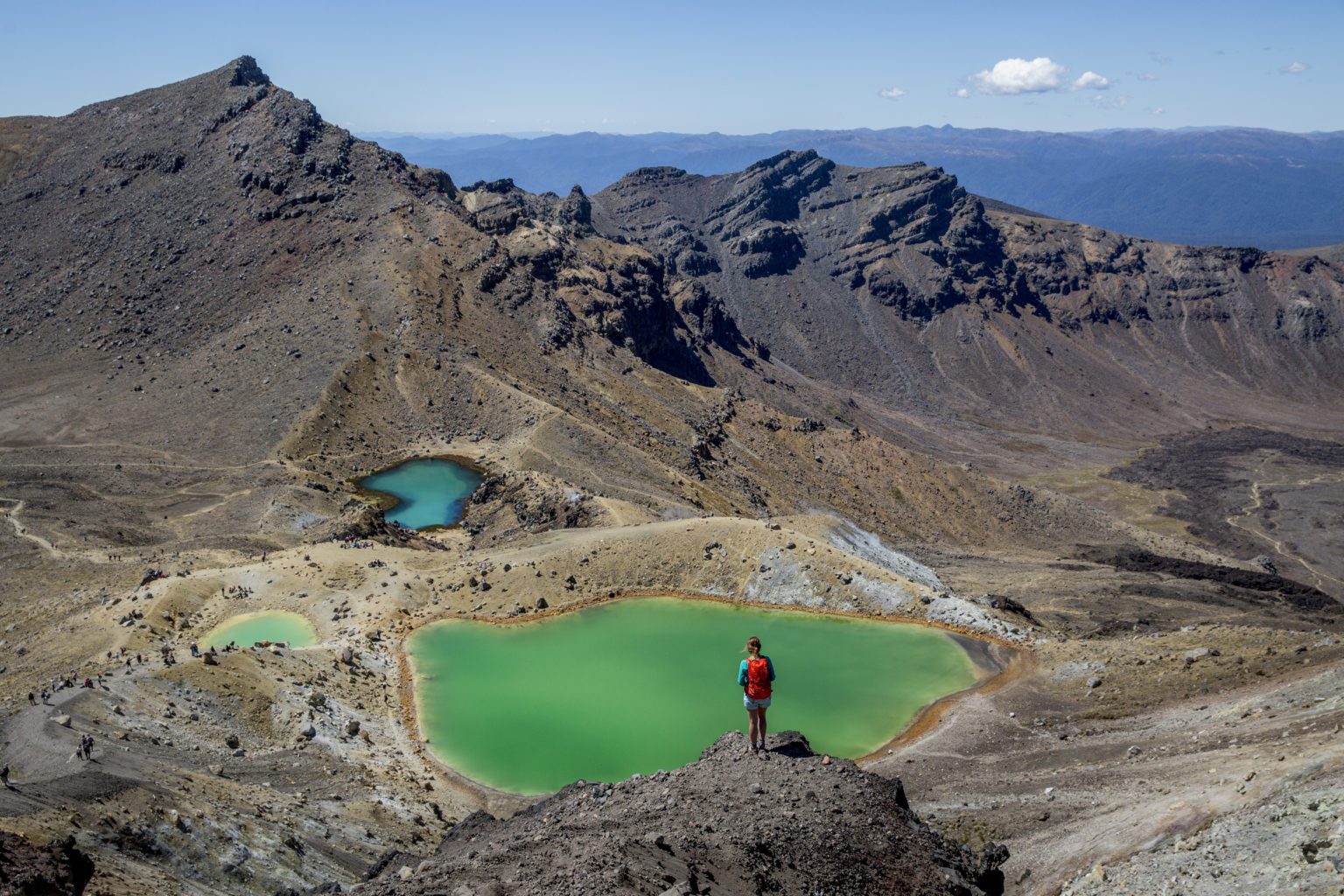 A hiker stops to admire the green lake on the Tongariro Alpine Crossing