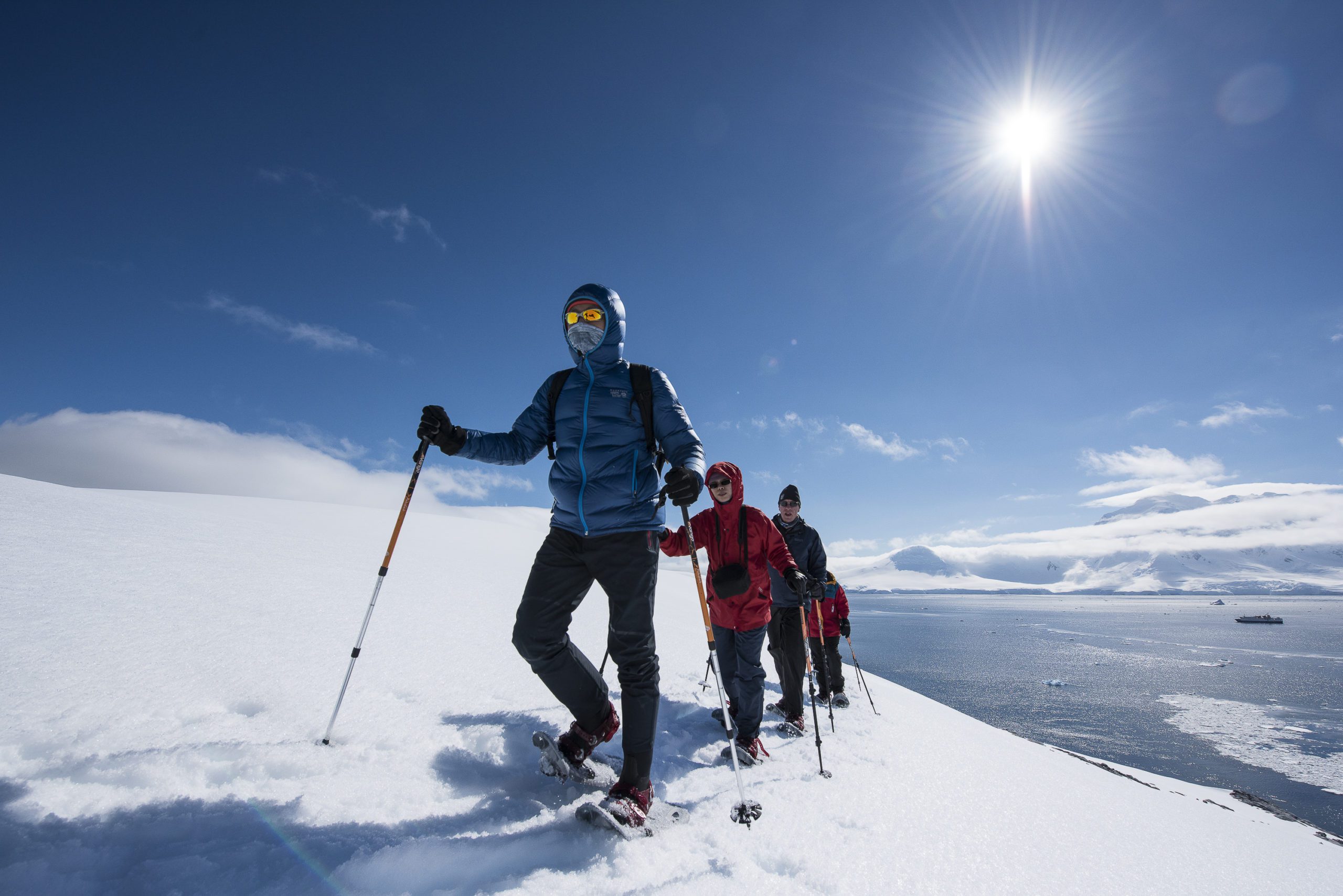 hikers trekking through the snow on a sunny blue sky day on the Antarctic Peninsula
