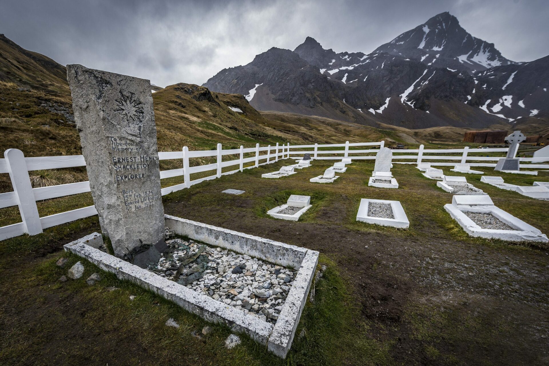 the tomb of explorer Ernest Shackleton in a small graveyard with mountains in the background