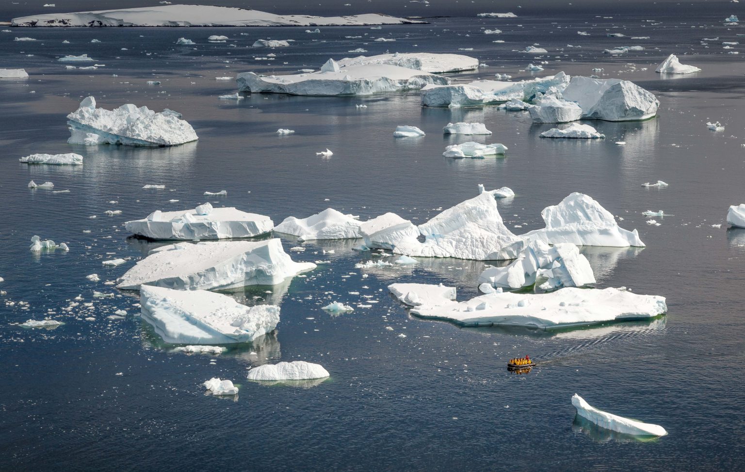 zodiac boat dwarfed by the size of the icebergs floating in the Antarctic waters
