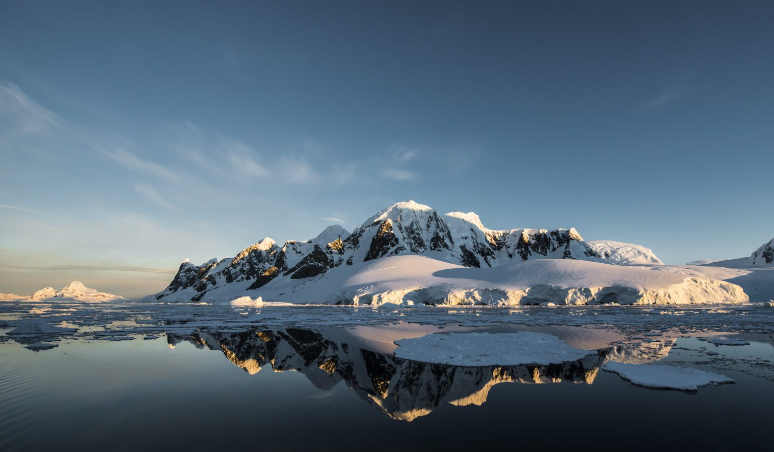 mirror reflection in the icy waters of snow capped mountains on the Antarctic Peninsula