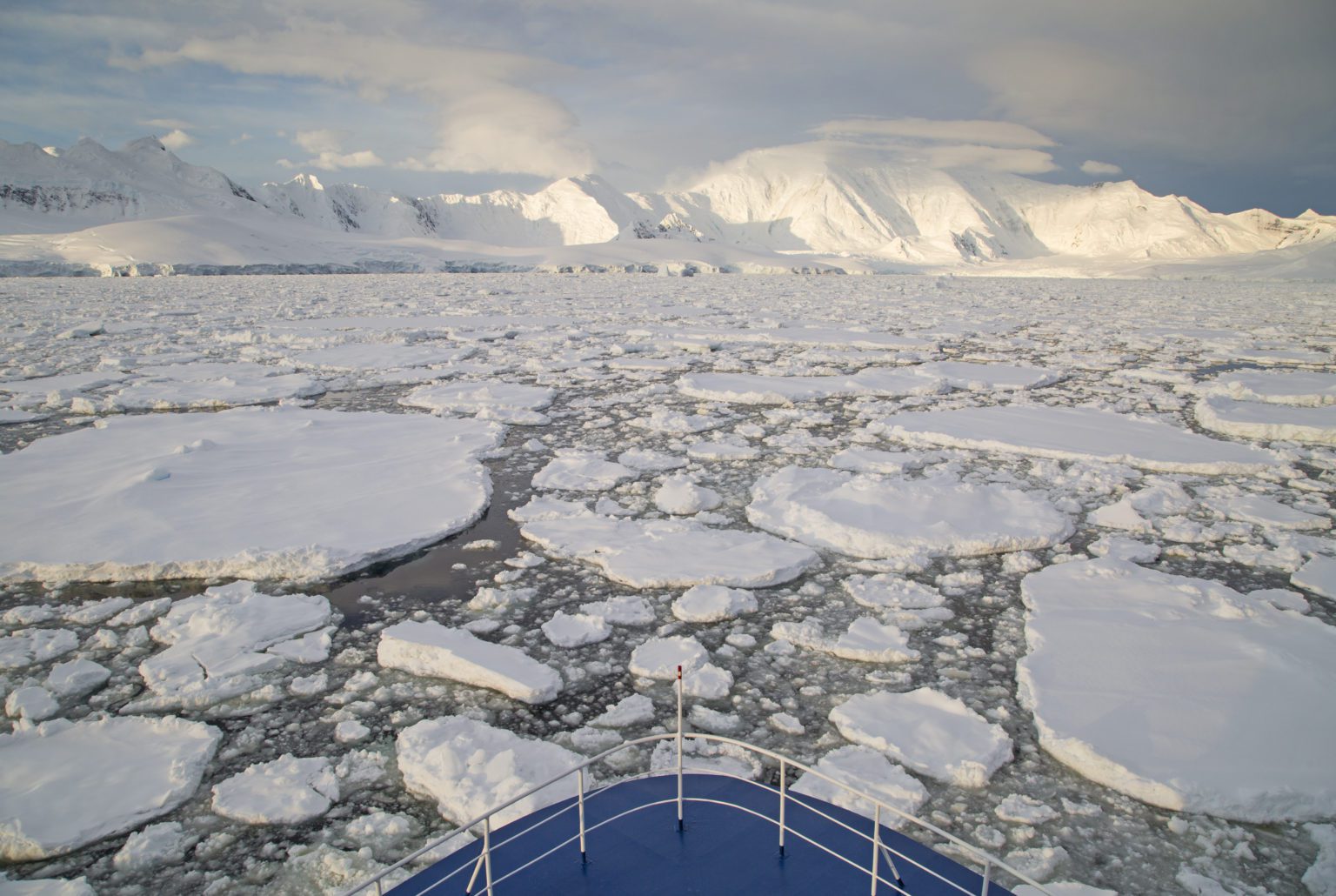 bow of ship breaking through broken up ice in the Antarctic seas