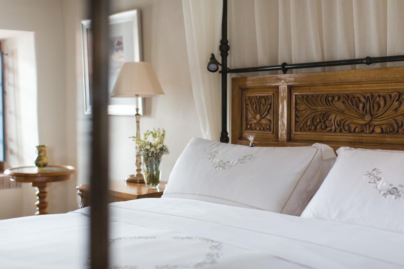 Hotel bed with white sheets and wooden headboard