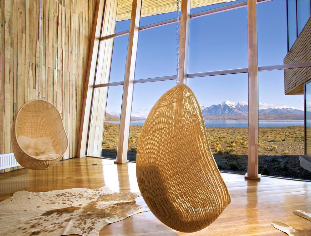 woven chairs hangning in front of glass windows looking out to mountains