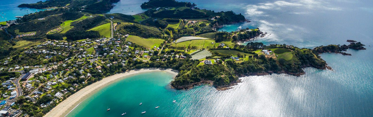 aerial view over waiheke island showing the turquoise water and green interior of the island on New Zealand tour