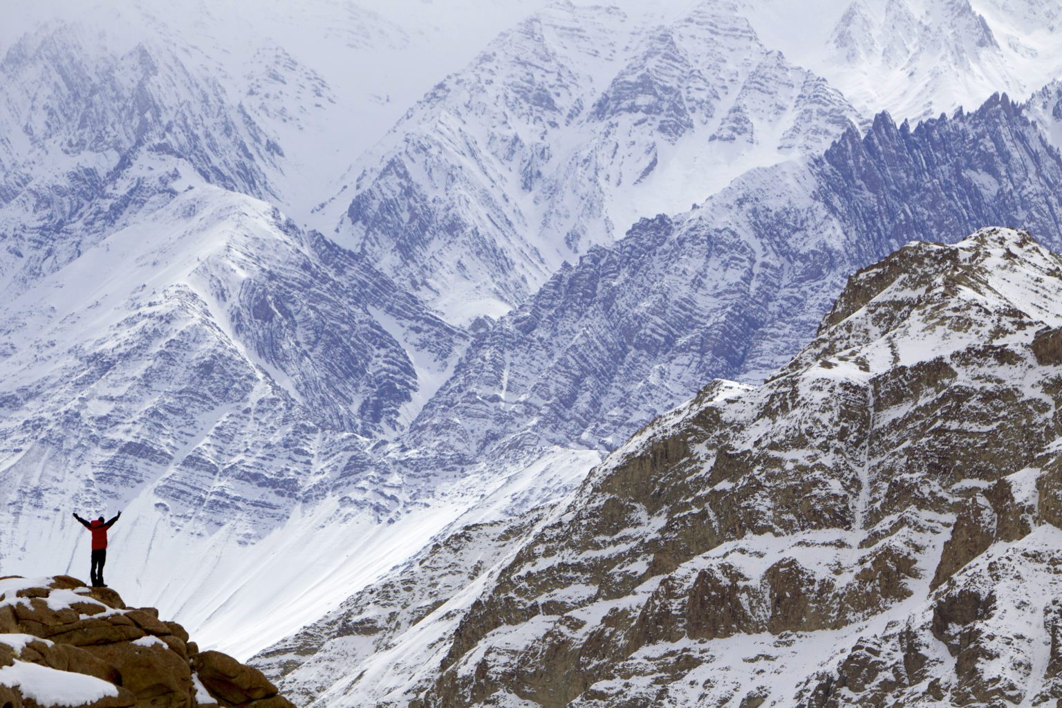 small person standing on a rock to see the enormity of the surrounding mountains