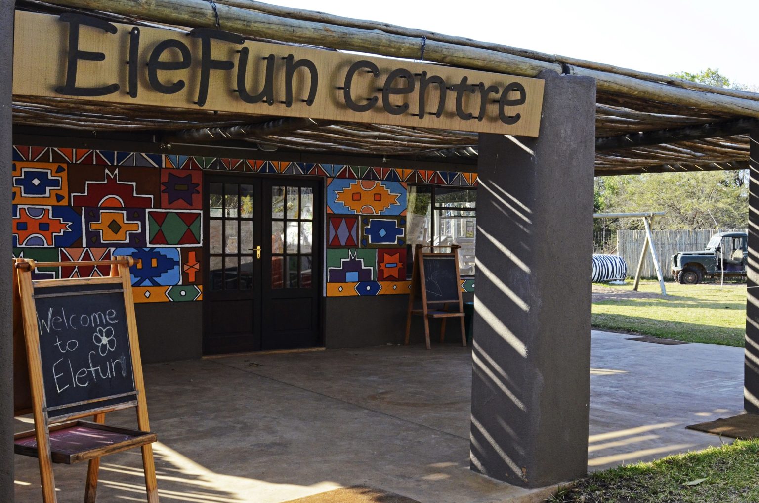 exterior of the brightly painted EleFun Centre with a welcome chalkboard outside.