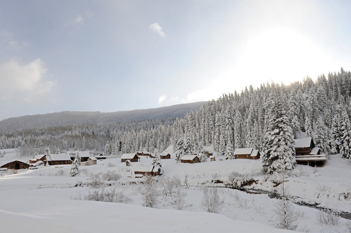 cabins, trees, and river covered in snow on a clear day