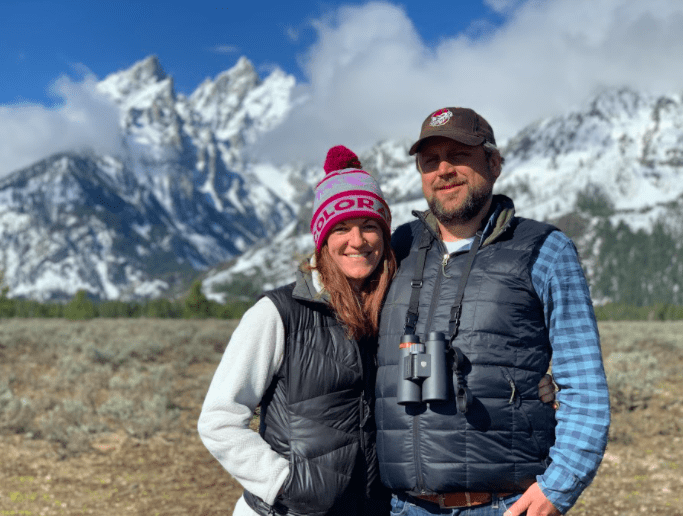 Serious Wildlife Seekers will Love a Quiet Spring or Fall Weekend in Jackson Hole, A man and woman smile while standing in front of the the Grand Teton Mountains