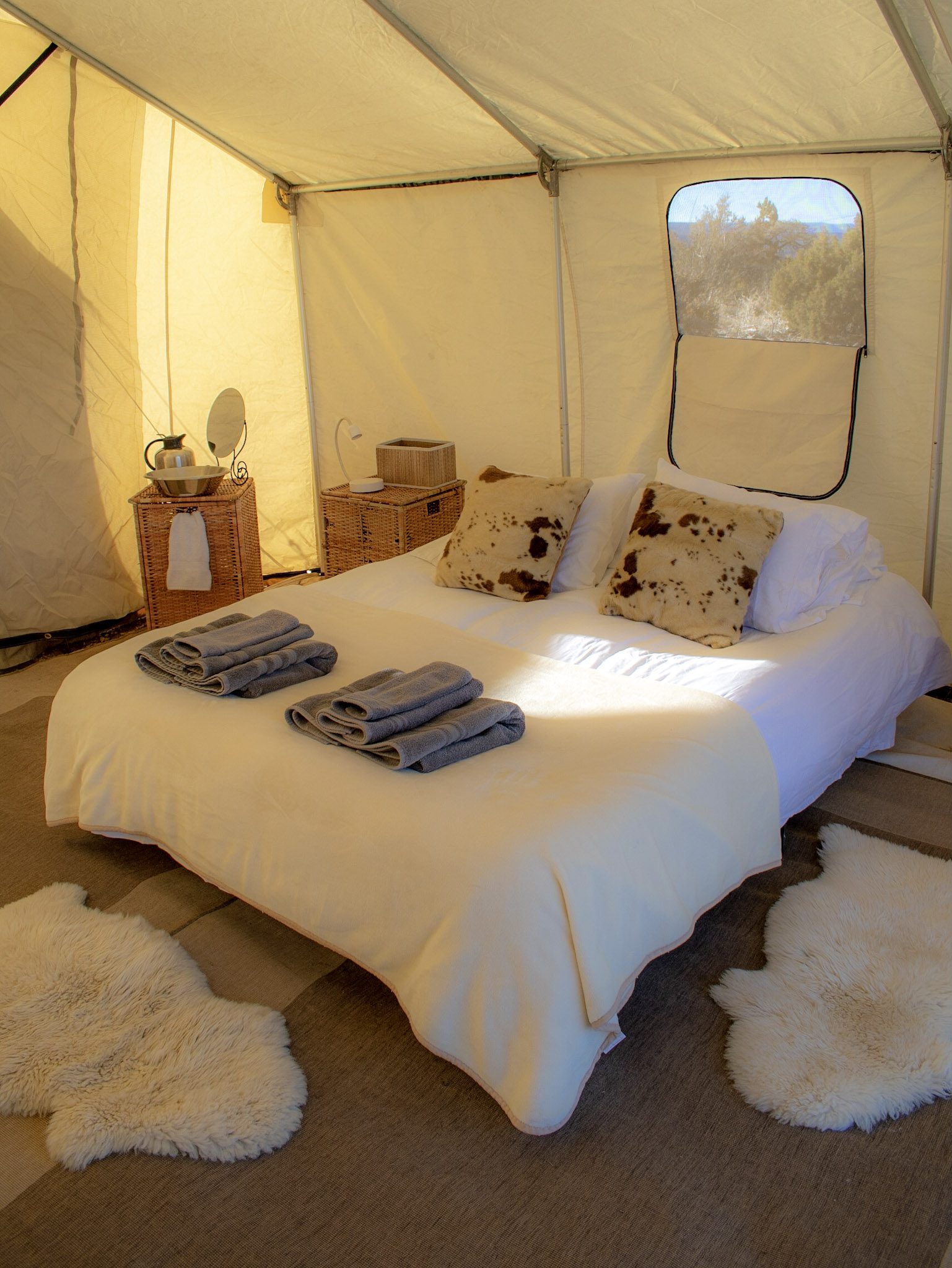 white linen bed with fur rugs in a tent at the Grand Canyon