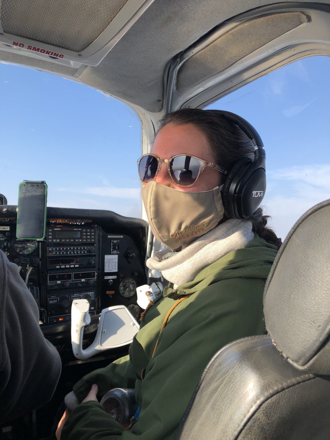 a woman wearing a face mask sitting in the cockpit of a plane.