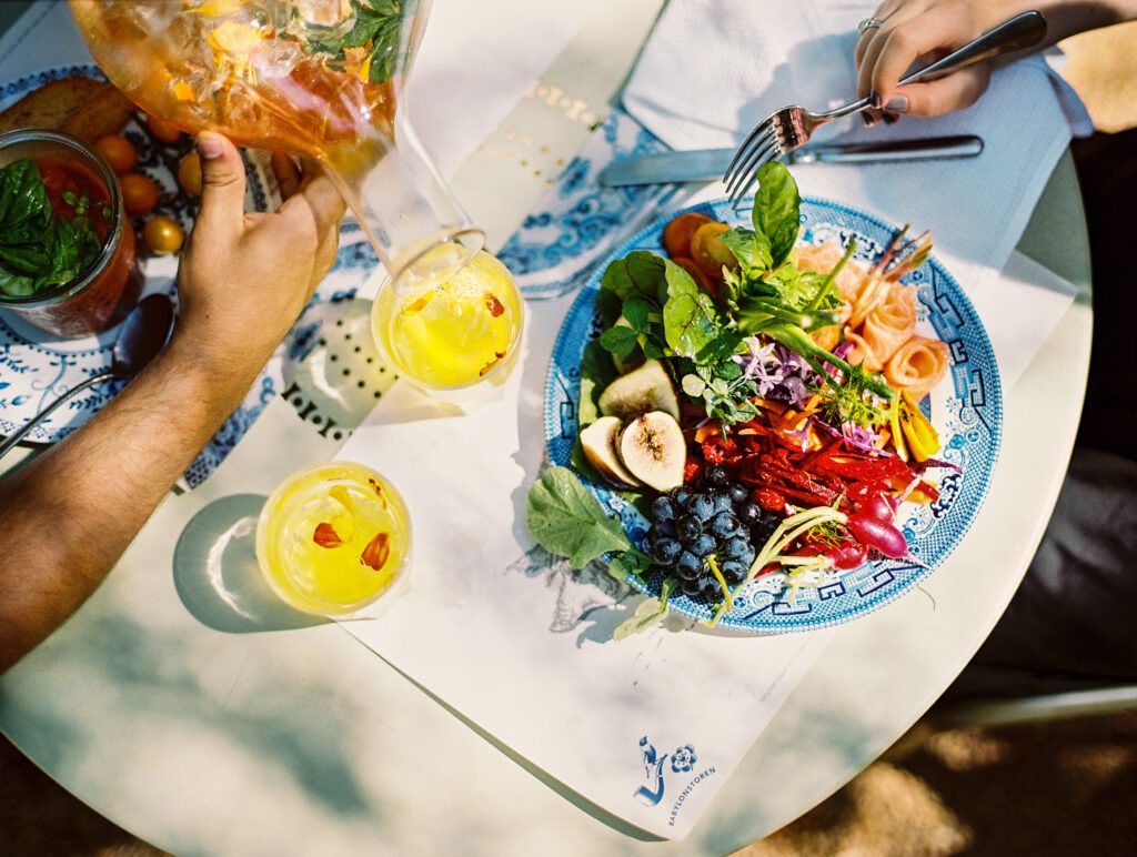 outdoor table setup with colorful spring time salad and refreshing herbal tea being poured into glasses 