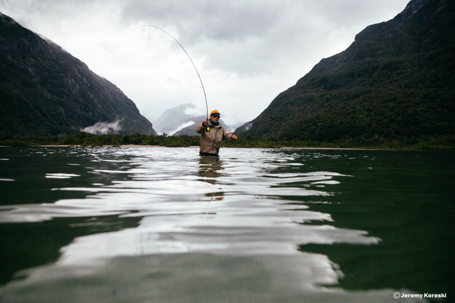 a man standing in the water while holding a fishing rod.