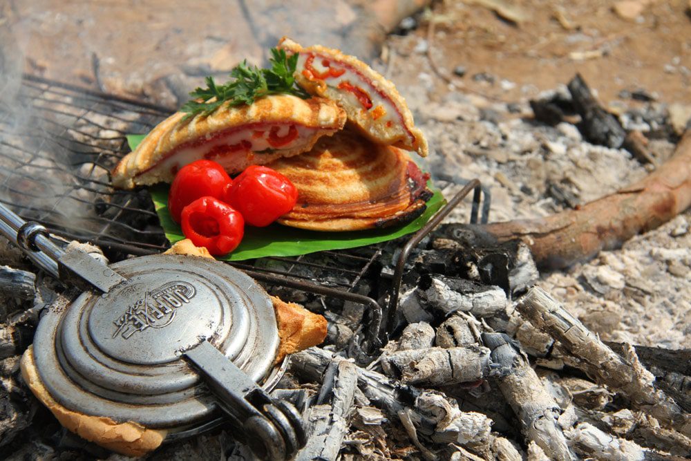 some food is cooking on a grill on the ground.