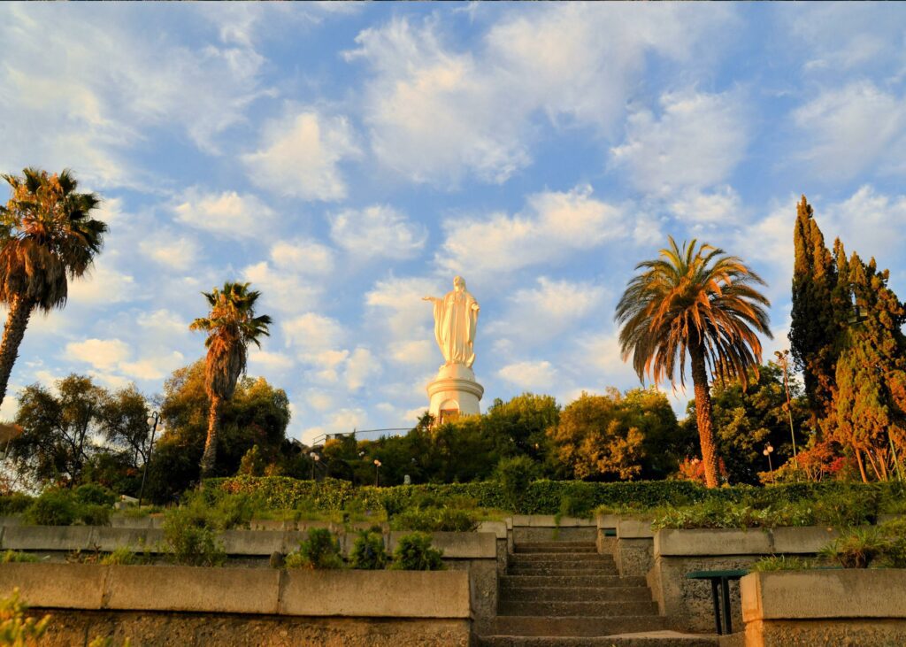 A statue of the Virgin Mary among palm tree on top of Cerro San Cristobal