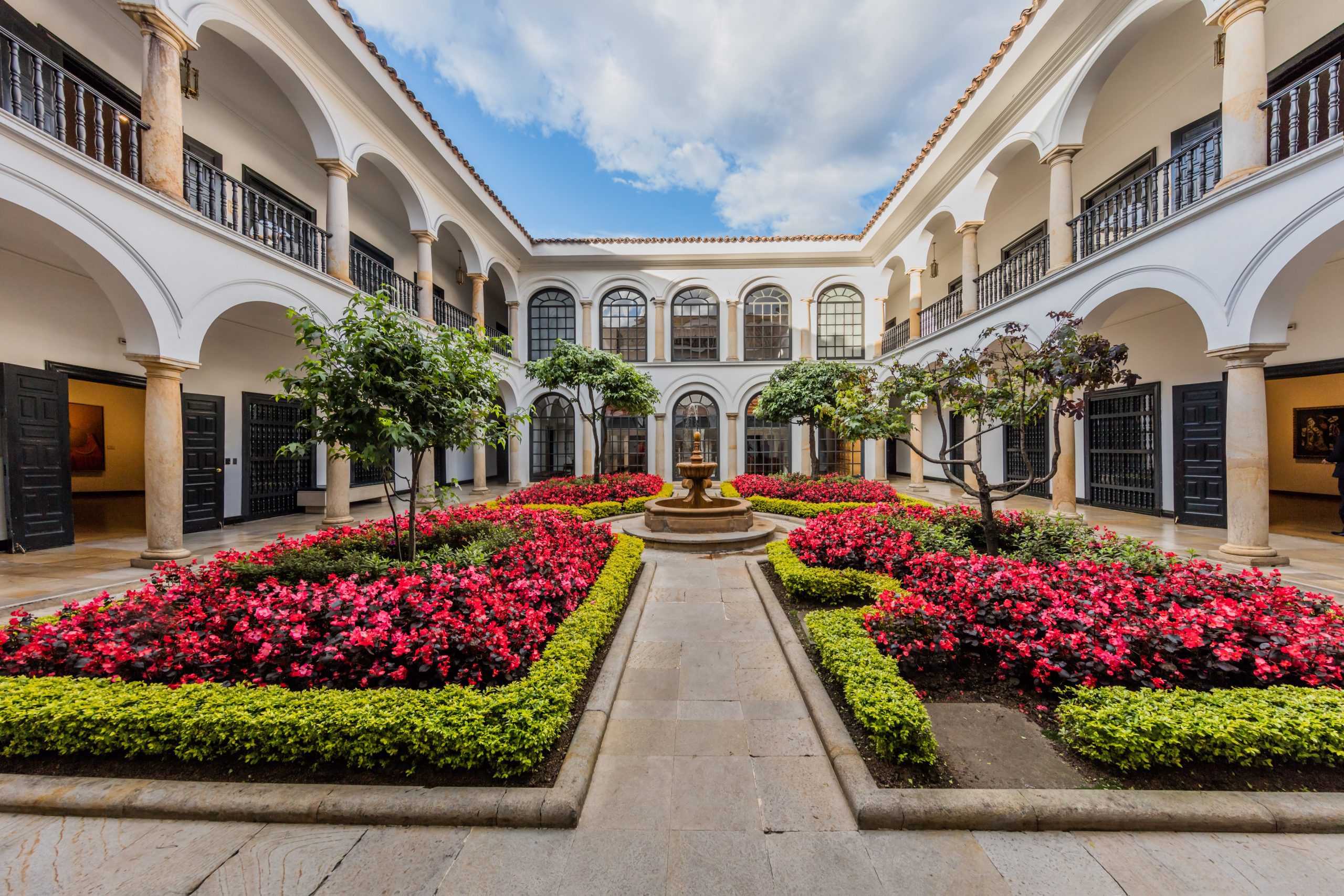 a courtyard with a fountain surrounded by flowers.