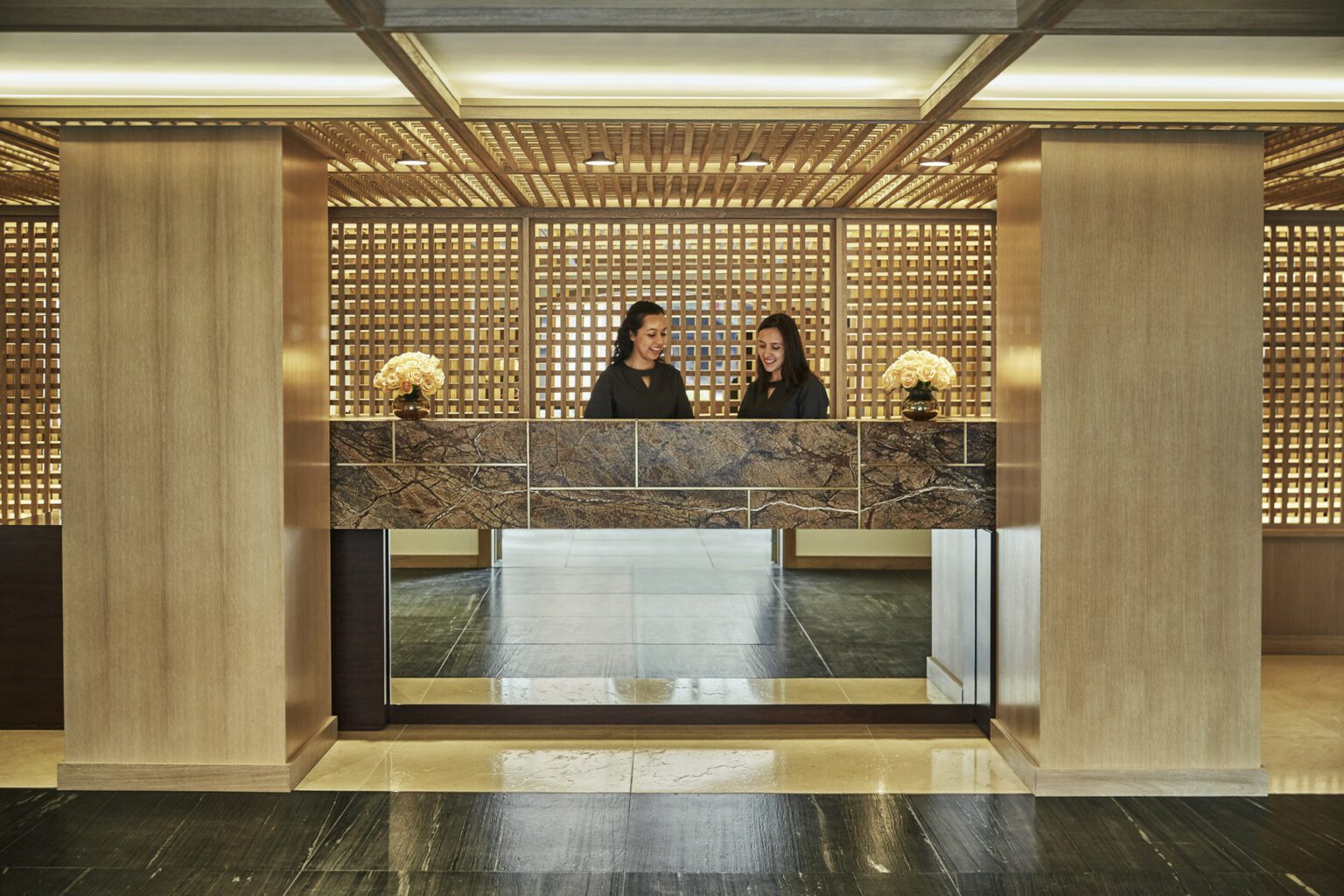 two women standing in front of a counter in a lobby.