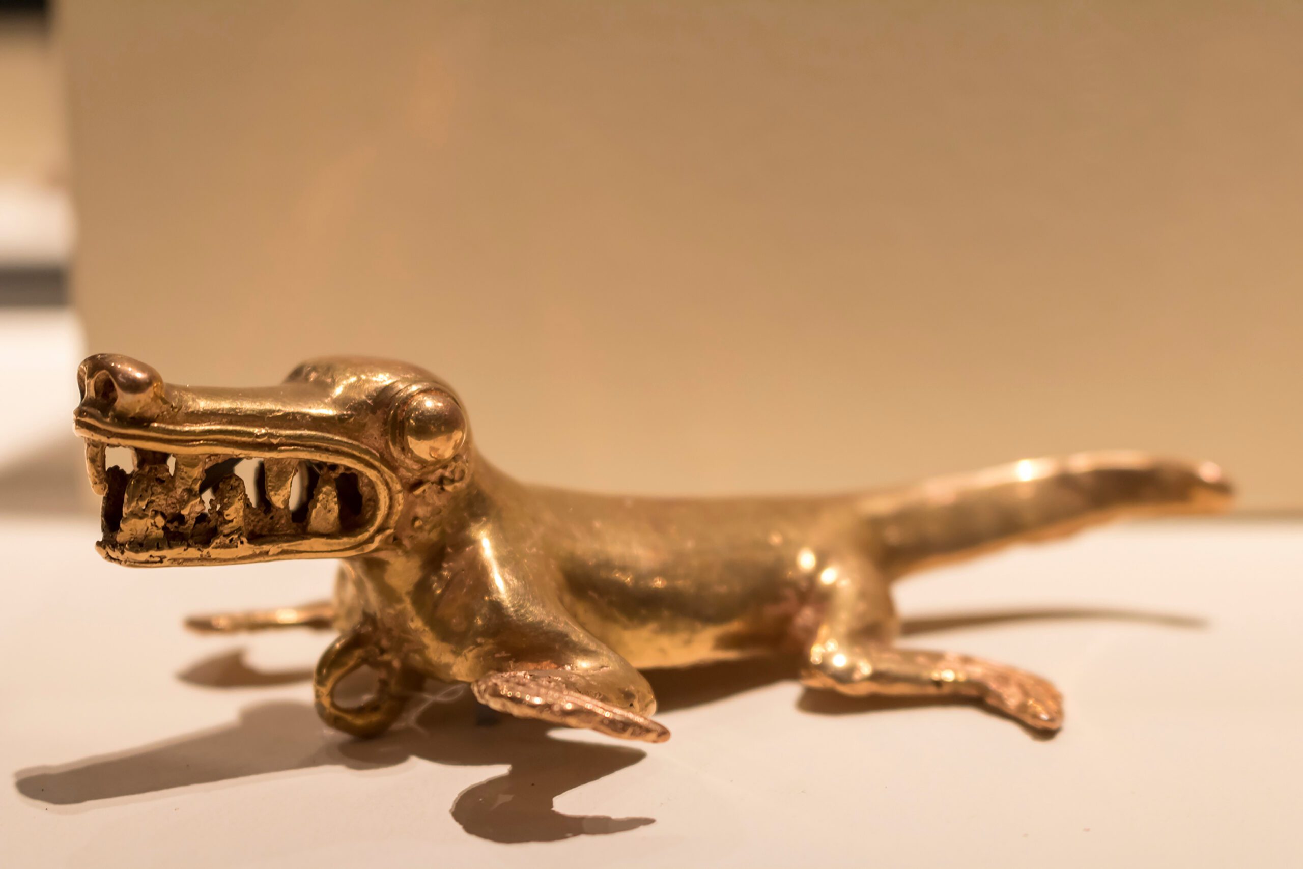a gold toy of a lizard on a white surface.