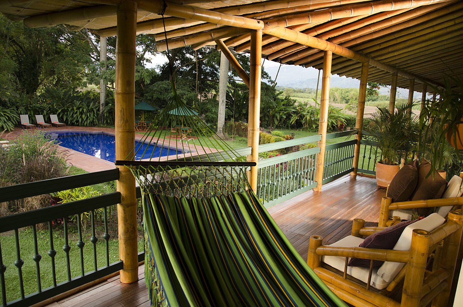 a porch with a hammock and a pool in the background.