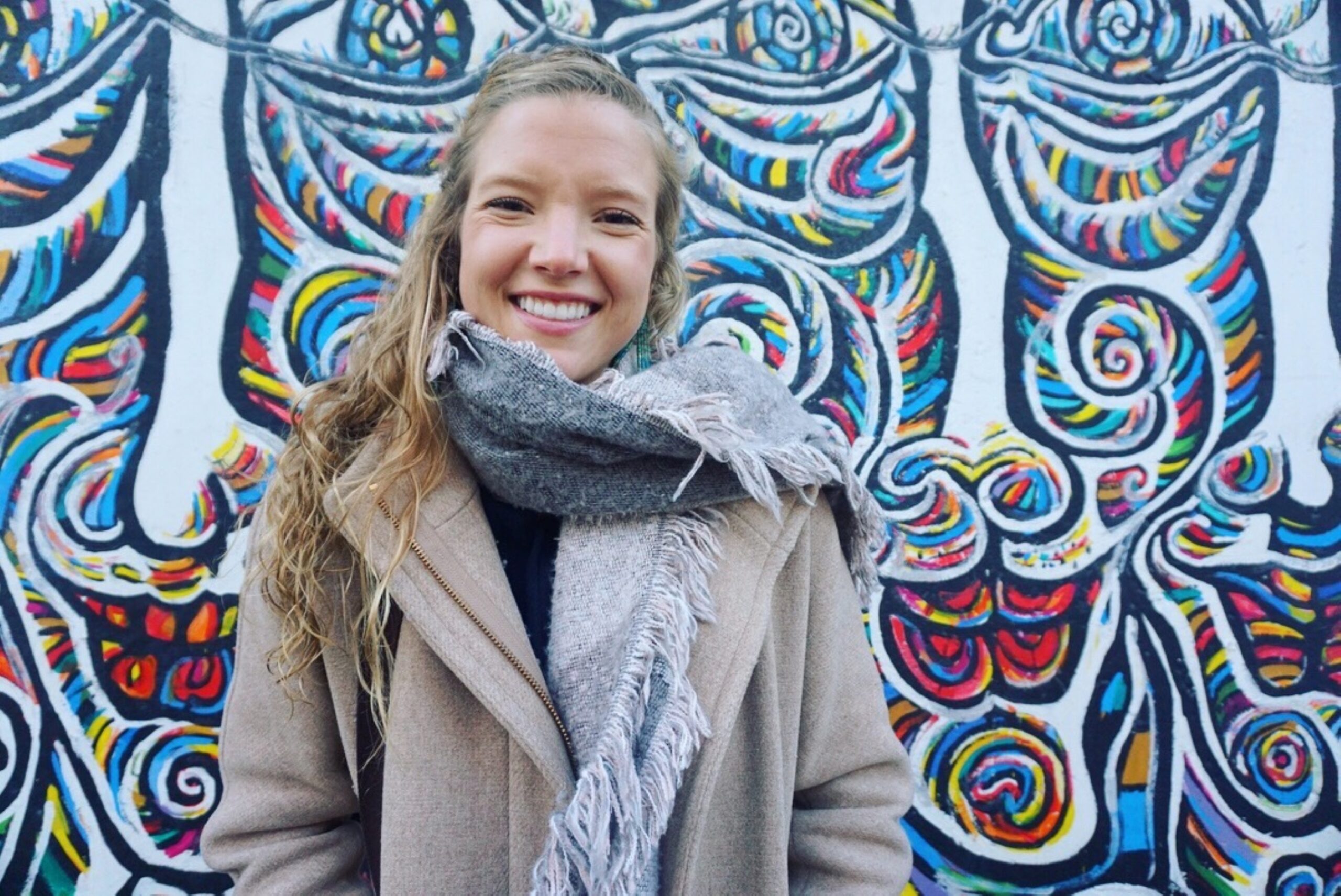 a woman standing in front of a colorful wall.