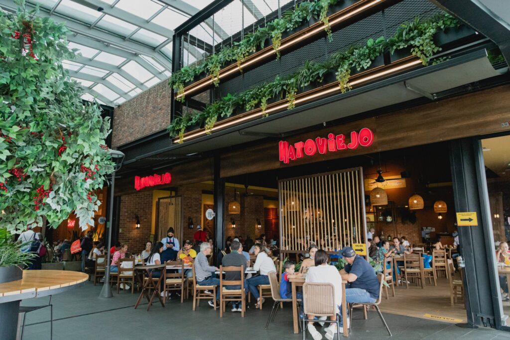 Street view of the Hatoviejo restaurant's Medellin location, with plenty of dinners and dining tables in view throughout the restaurant as there is no wall separating the restaurant from the outside.