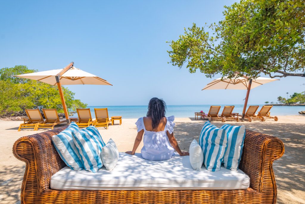 beach goer sits on a wicker lounger with her back to the camera looking over the private beach at Casa San Agustin  
